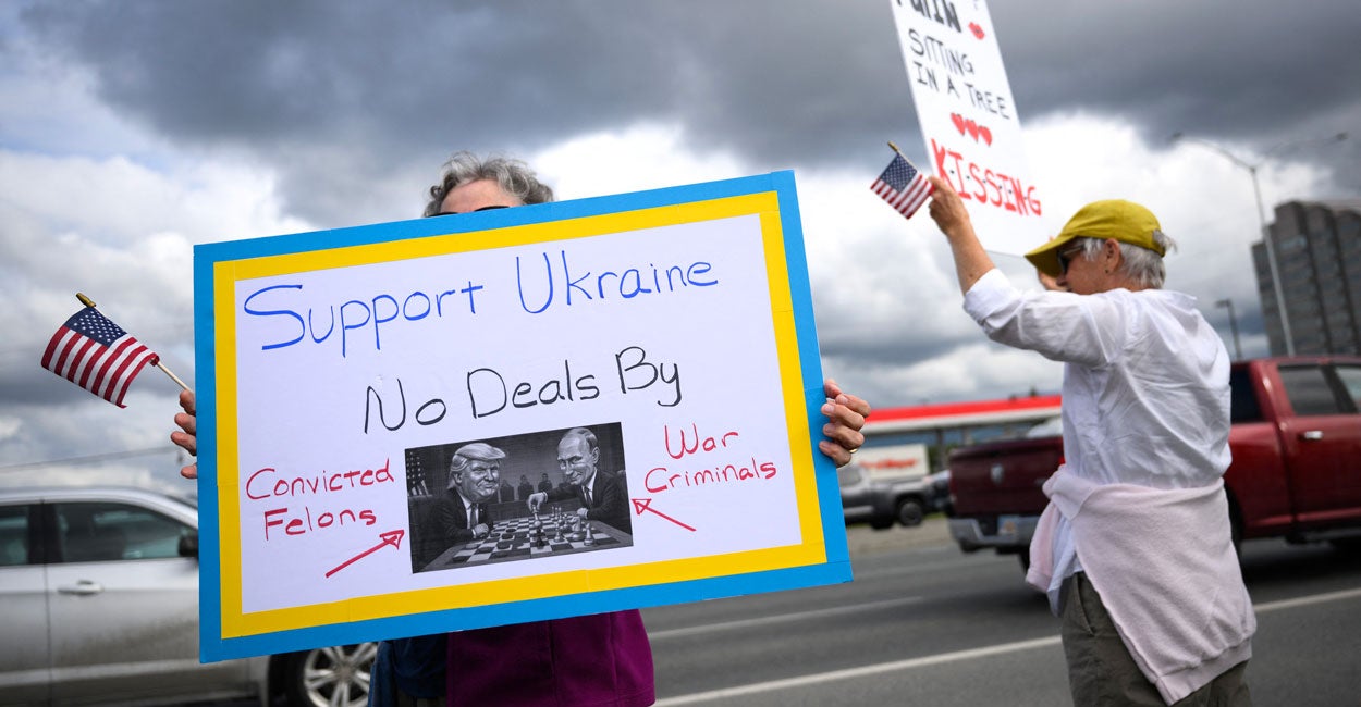 Protester stands with a blue and yellow-trimmed sign with a caricature of Trump and Putin playing chess, with the sign reading "Support Ukraine No Deals By Convicted Felons, War Criminals."