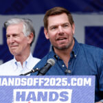 Eric Swalwell behind a podium reading "Handsoff2025.com"