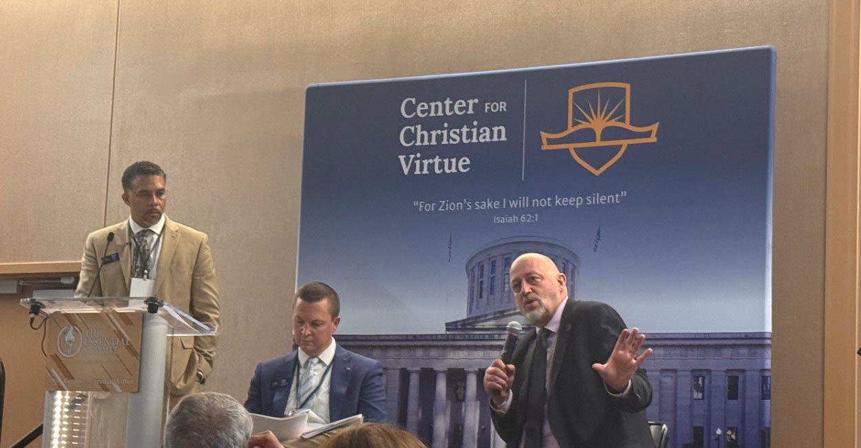 State Rep. Gary Click sits in front of a banner for the Center for Christian Virtue at their Essential Summit. 