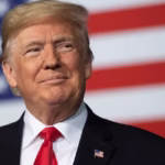 Donald Trump smiling in front of a U.S. flag