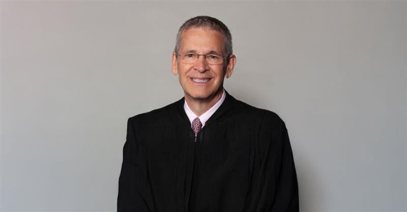 Judge John McConnell, smiling, in his black robe. 